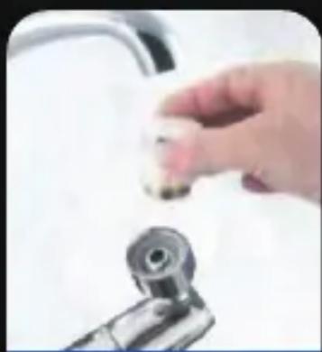 Hand holding a small object near a kitchen sink (no visible text or symbols)