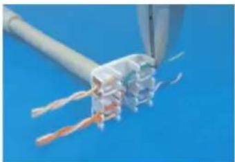 Close-up of a white cable being inserted into a terminal block against a blue background (no text or symbols visible)