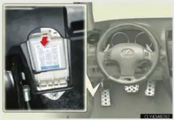 Car interior control panel with battery display and steering wheel, showing a red arrow pointing to the battery.