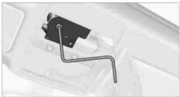 Close-up of a mechanical component with a black bracket and wire, mounted on a white surface (no visible text or symbols)