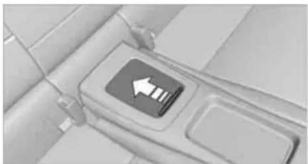 Close-up of a car interior showing a directional arrow pointing to a button (no text or symbols visible)