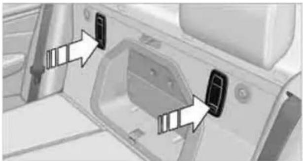 Close-up of a car's front panel showing two black buttons with white arrows pointing to the door (no text or symbols visible)