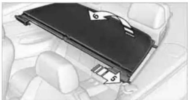 Interior view of a car showing a black plastic cover with numbered arrows pointing to its side (no text or symbols present)