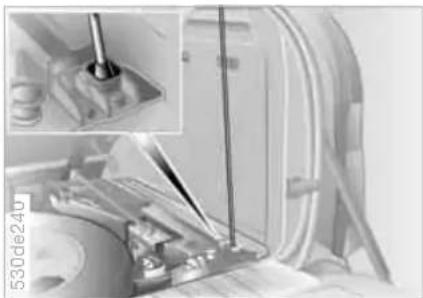 Close-up of a mechanical assembly with a tool inserted, showing internal components and a magnified inset (no visible text or symbols)