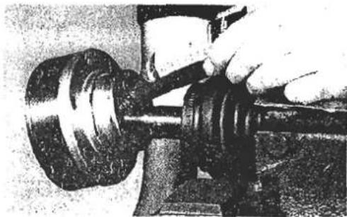 Close-up of a hand using a gavel to adjust or install a mechanical component (no visible text or symbols)