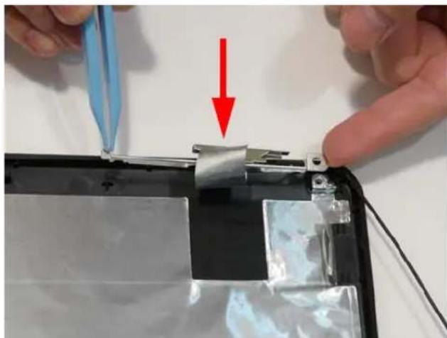 Close-up of hands using a tool to remove or repair a flexible electronic component, with a red arrow indicating the process (no text or symbols visible).