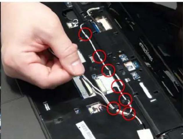 Close-up of a hand inserting wires into a laptop case, with red circles highlighting specific components (no text or symbols visible)