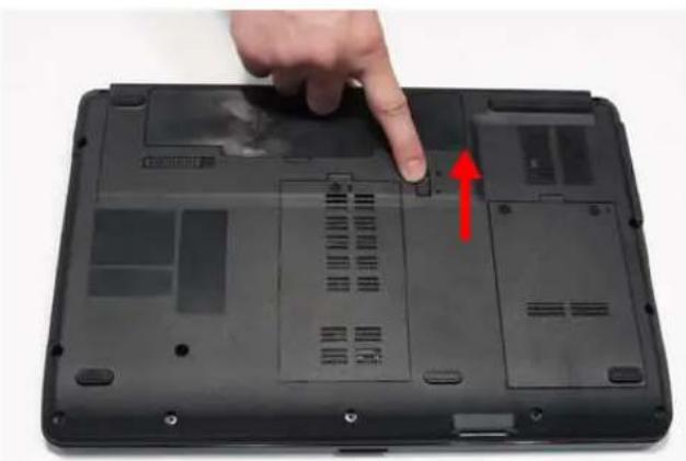 Close-up of a black laptop with visible internal components and a hand pointing to a button, marked with a red arrow (no text or symbols)