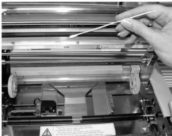 Close-up of a hand using a tool to adjust or install electronic components, with visible warning label and warning sign.