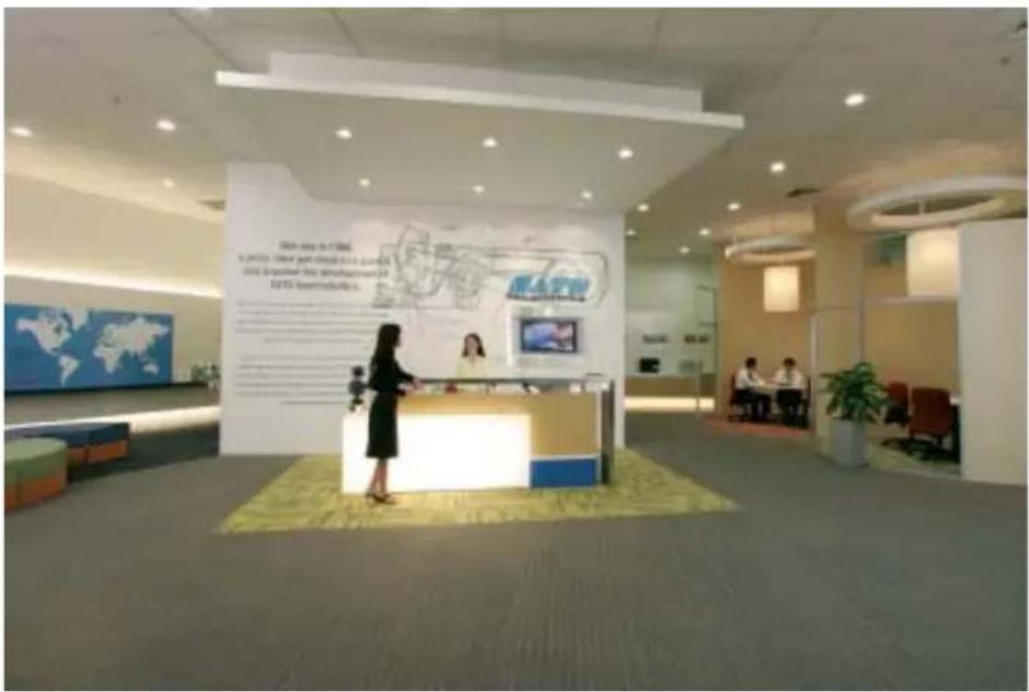 Interior photo of a modern office lobby with visible signage and reception desk, featuring Chinese text on wall panels and wall-mounted screens.