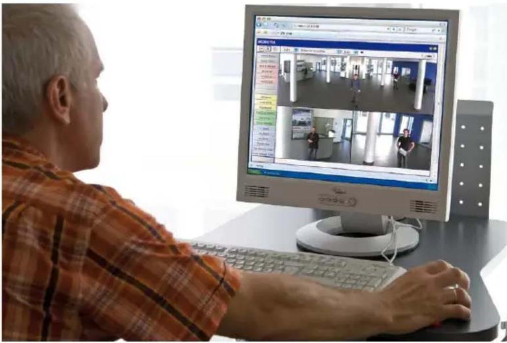 Person using a computer displaying a video call interface with multiple video frames and user interactions in an office setting.