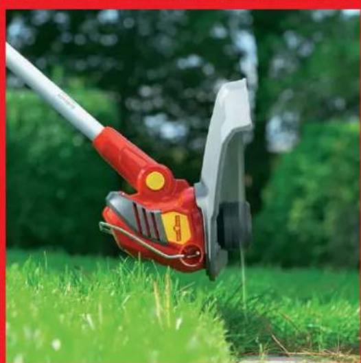 Close-up of a red and white lawn shaver on grass, with blurred green trees in the background (no text or symbols visible)