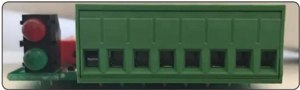 Green electronic component with multiple slots and a red traffic light indicator (no text or symbols visible)