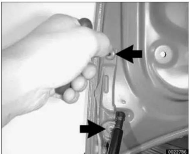 Close-up of a hand using a tool to adjust or install a mechanical component, with arrows pointing to specific parts (no visible text or symbols)