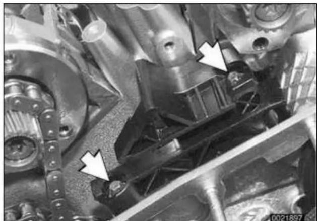 Close-up mechanical assembly with white arrows pointing to specific components (no visible text or symbols).