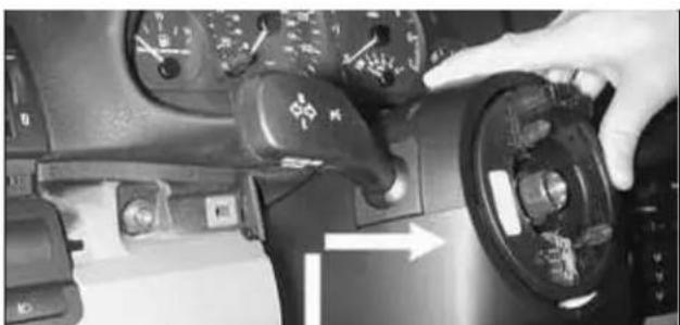 Close-up of a car's dashboard and steering wheel with hand pointing to the control panel (no visible text or symbols)