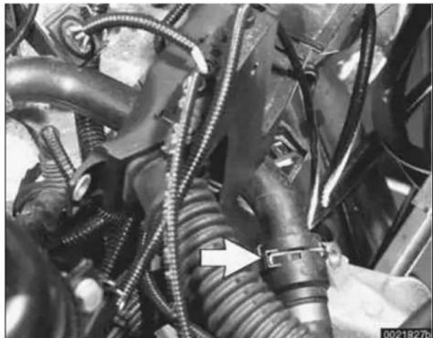 Close-up of automotive engine components with hoses and a white arrow pointing to a component (no visible text or symbols)