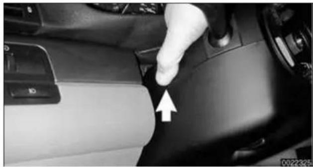 Close-up of a car interior showing a hand pressing down the dashboard with an arrow pointing to the left side (no text or symbols visible)