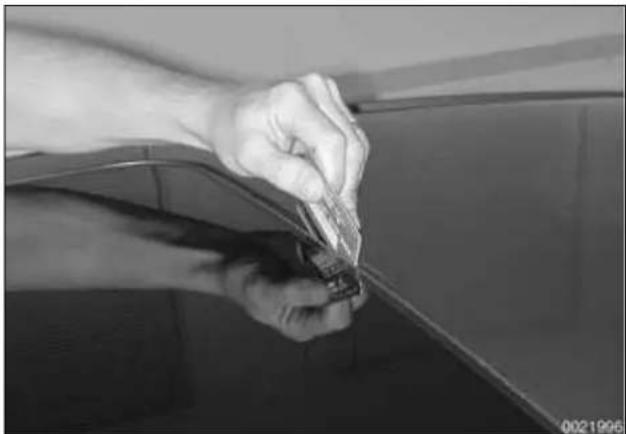 Close-up of hands holding a small electronic component, possibly a connector, with no visible text or symbols.