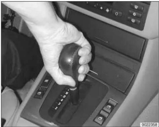 Close-up of a hand using a black gear shift on a car intake console.