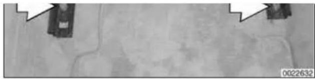 Grayscale aerial or satellite view of a road with visible cracks and two small structures, no text or symbols present.