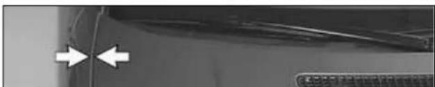Close-up of a car's side panel with two white arrows pointing to the front edge (no visible text or symbols)