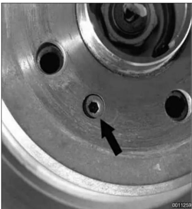 Close-up of a mechanical component with a bolt hole and a black arrow pointing to it (no text or symbols visible)
