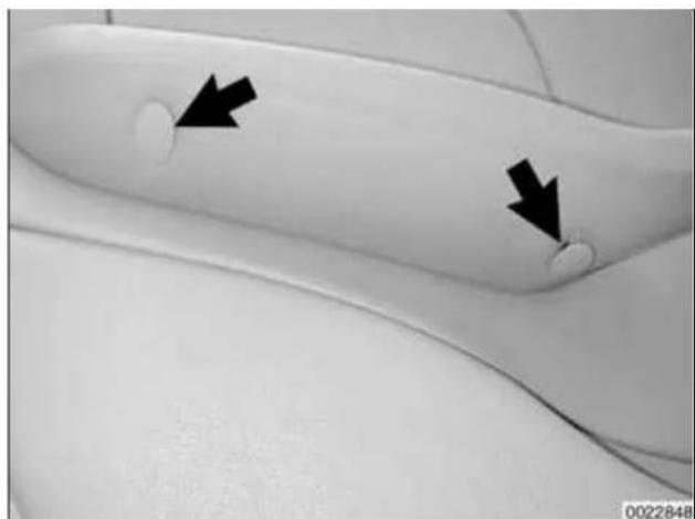 Close-up of a curved, white object with two black arrows pointing to circular features (no text or symbols visible)