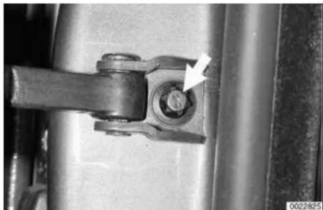 Close-up of a mechanical component with a bolt and nut, showing a white arrow pointing to a hole (no text or symbols visible).