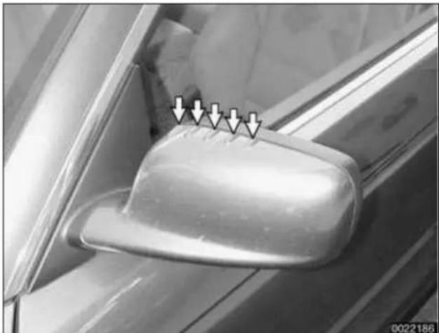 Close-up of a car's side mirror with white arrows pointing to the lens (no text or symbols visible)