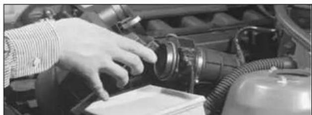 Close-up of a hand adjusting a mechanical component in an engine bay (no visible text or symbols).