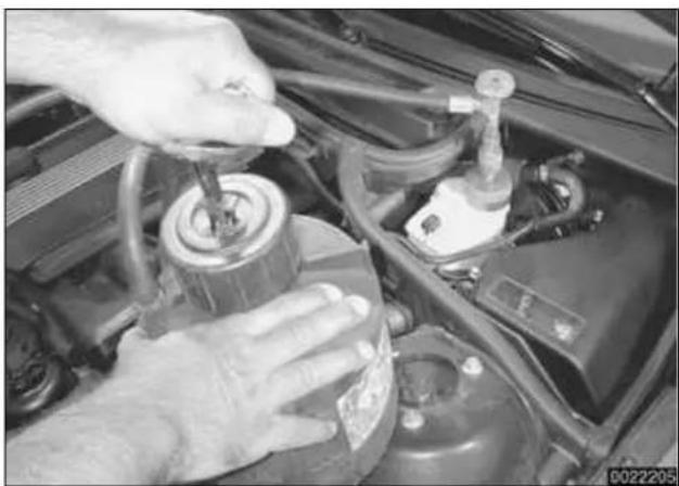 Close-up of hands adjusting a car engine component with a tool (no visible text or symbols)