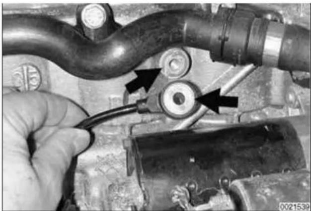 Close-up of a hand holding a cable connected to a mechanical component, with arrows pointing to specific parts (no visible text or symbols)