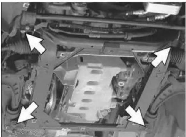 Close-up of an automotive engine bay with white arrows pointing to structural components (no visible text or symbols)