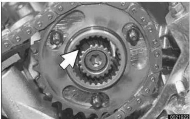 Close-up of a mechanical gear assembly with a white arrow pointing to a specific component (no text or symbols visible)