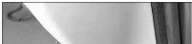 Close-up of a white surface with faint texture and a curved dark edge, possibly part of a material or document (no visible text or symbols)