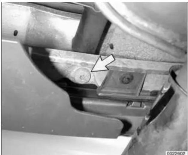 Close-up of a mechanical component with a white arrow pointing to a small feature, no visible text or symbols.