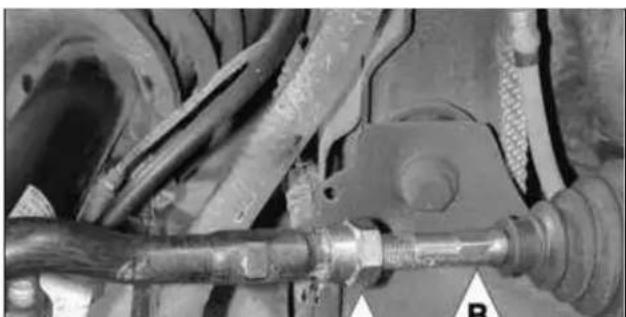 Close-up of automotive suspension system components including hoses and a valve (no visible text or symbols)