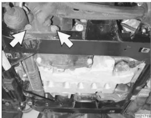 Close-up of an automotive engine bay with two white arrows pointing to specific components (no visible text or symbols)