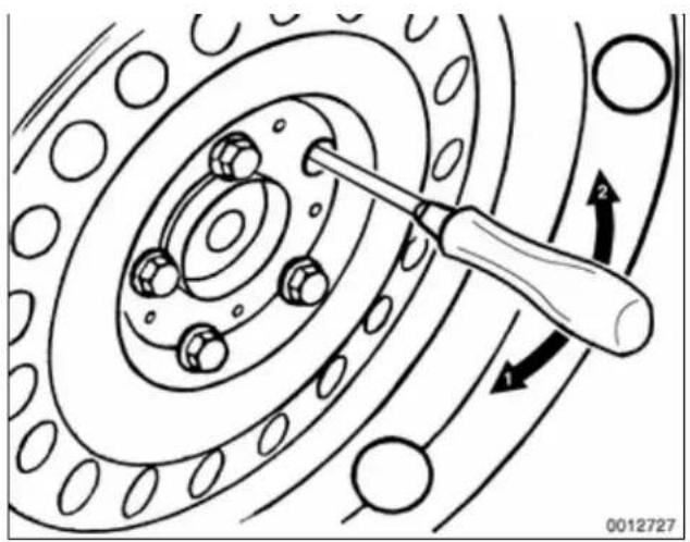 Technical diagram of a mechanical assembly with a screwdriver inserted into a circular component (no text or symbols)