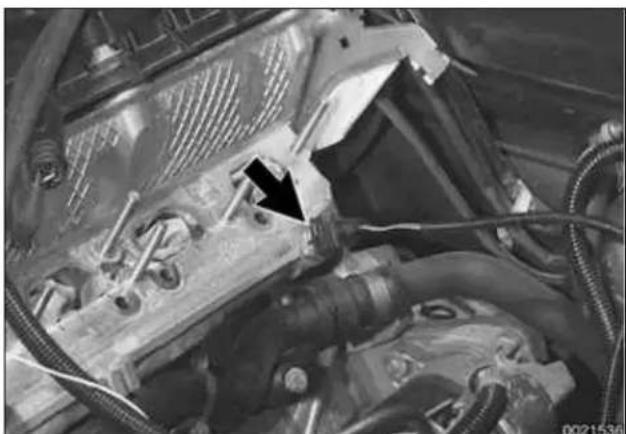 Close-up of an automotive engine bay with visible hoses and a black arrow pointing to a component (no text or symbols)