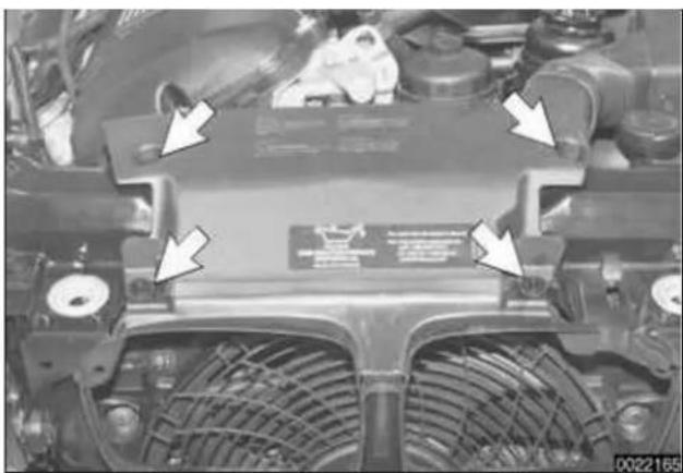 Close-up of a car engine head with visible structural components and directional arrows indicating assembly or inspection (no readable text or symbols)