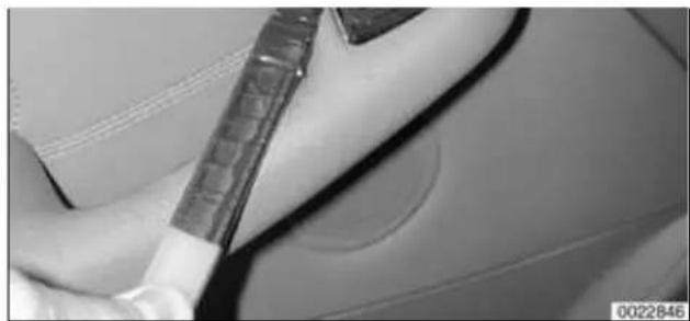 Close-up of a car interior showing a hand holding a tool near the dashboard (no visible text or symbols)