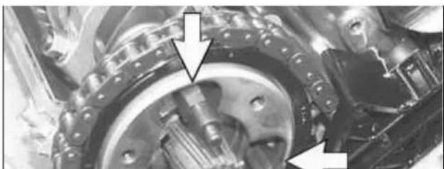 Close-up of a mechanical assembly with gears and shafts, showing two directional arrows pointing to specific components (no text or symbols visible)