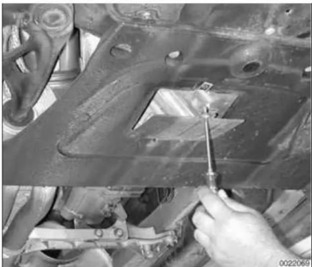 Close-up of a hand using a screwdriver to adjust or repair a mechanical component on a vehicle (no visible text or symbols)