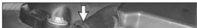 Close-up of a mechanical component with a downward arrow pointing to a small circular feature (no visible text or symbols)