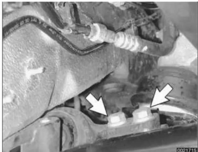 Close-up of a car brake caliper with white arrows pointing to the component (no visible text or symbols)