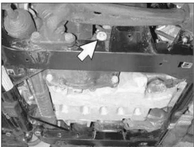 Close-up of an automotive engine bay with a white arrow pointing to a component (no visible text or symbols)