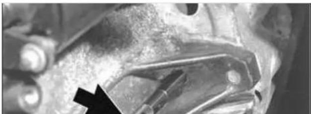 Close-up of mechanical components with a black arrow pointing to a specific part (no visible text or symbols)