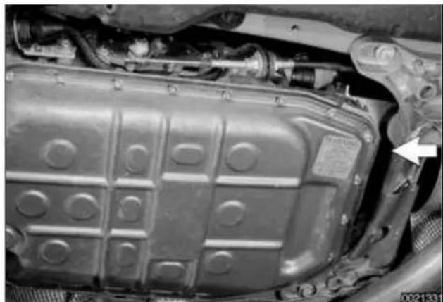 Close-up of an automotive battery pack with visible internal components and a white arrow pointing to a component (no text or symbols)